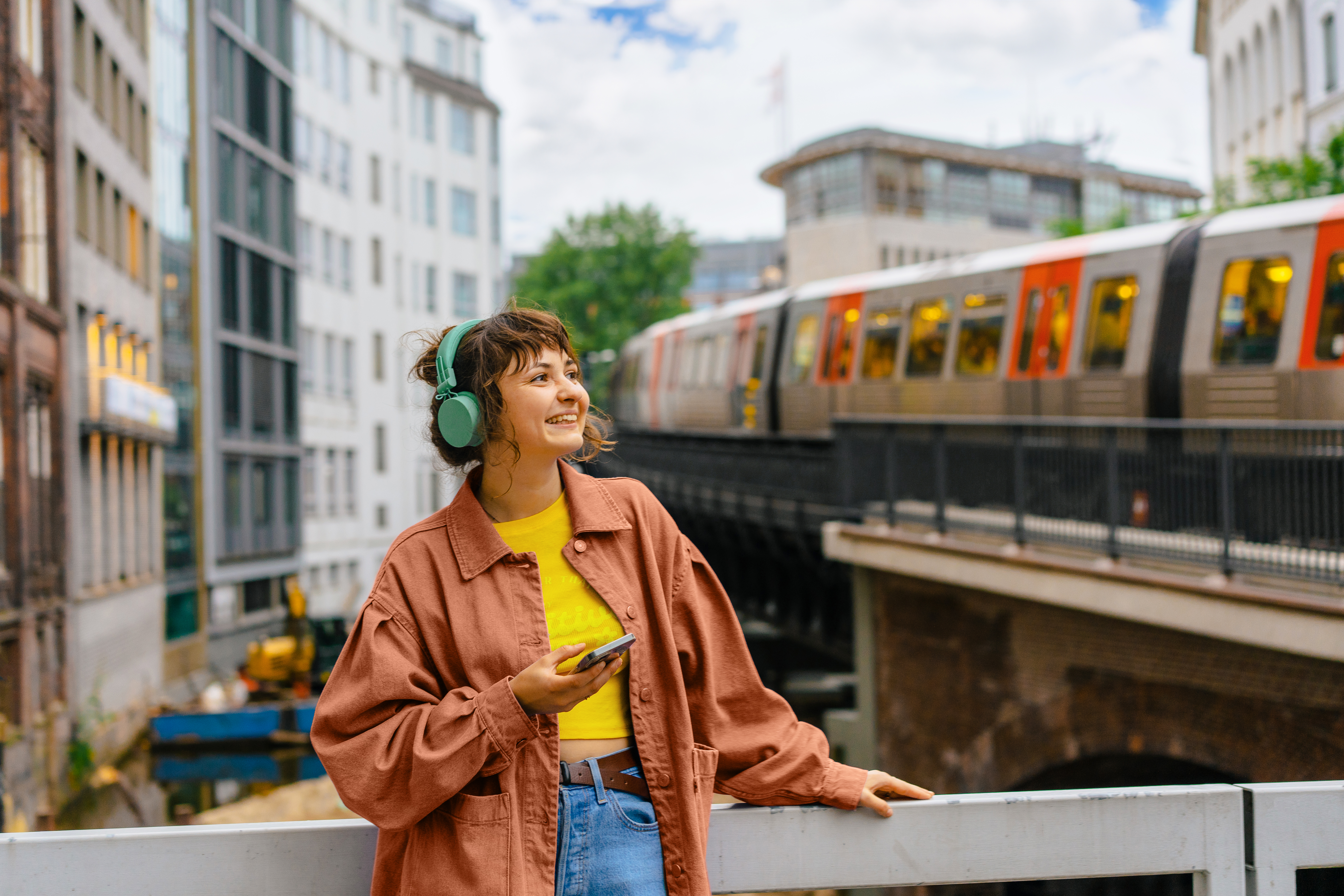 Mit öffentlichen Verkehrsmitteln flexibel unterwegs sein Junge Frau mit Kopfhörern steht vor U-Bahn