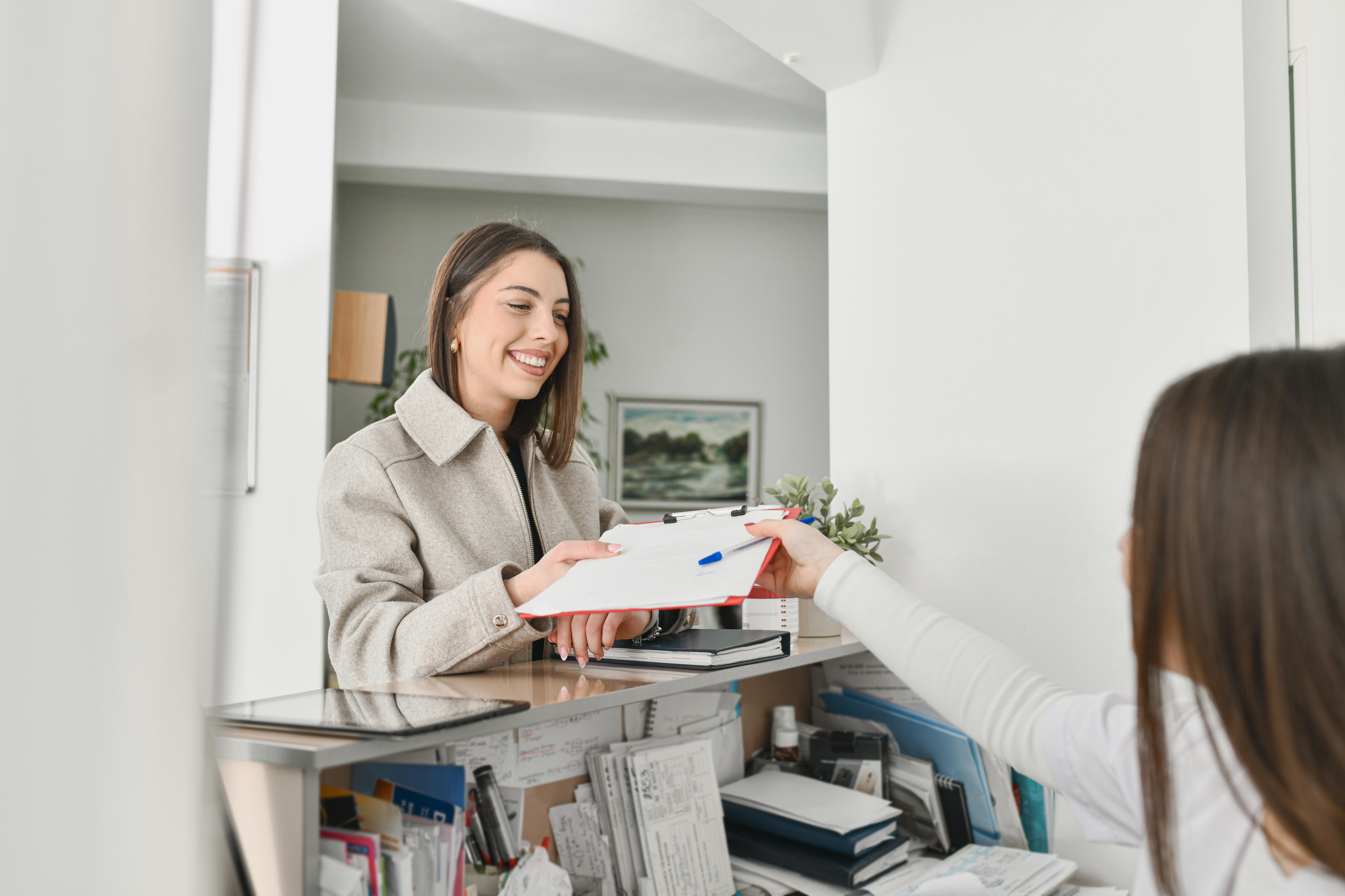 Female Hospital staff handing documents to young female patient.