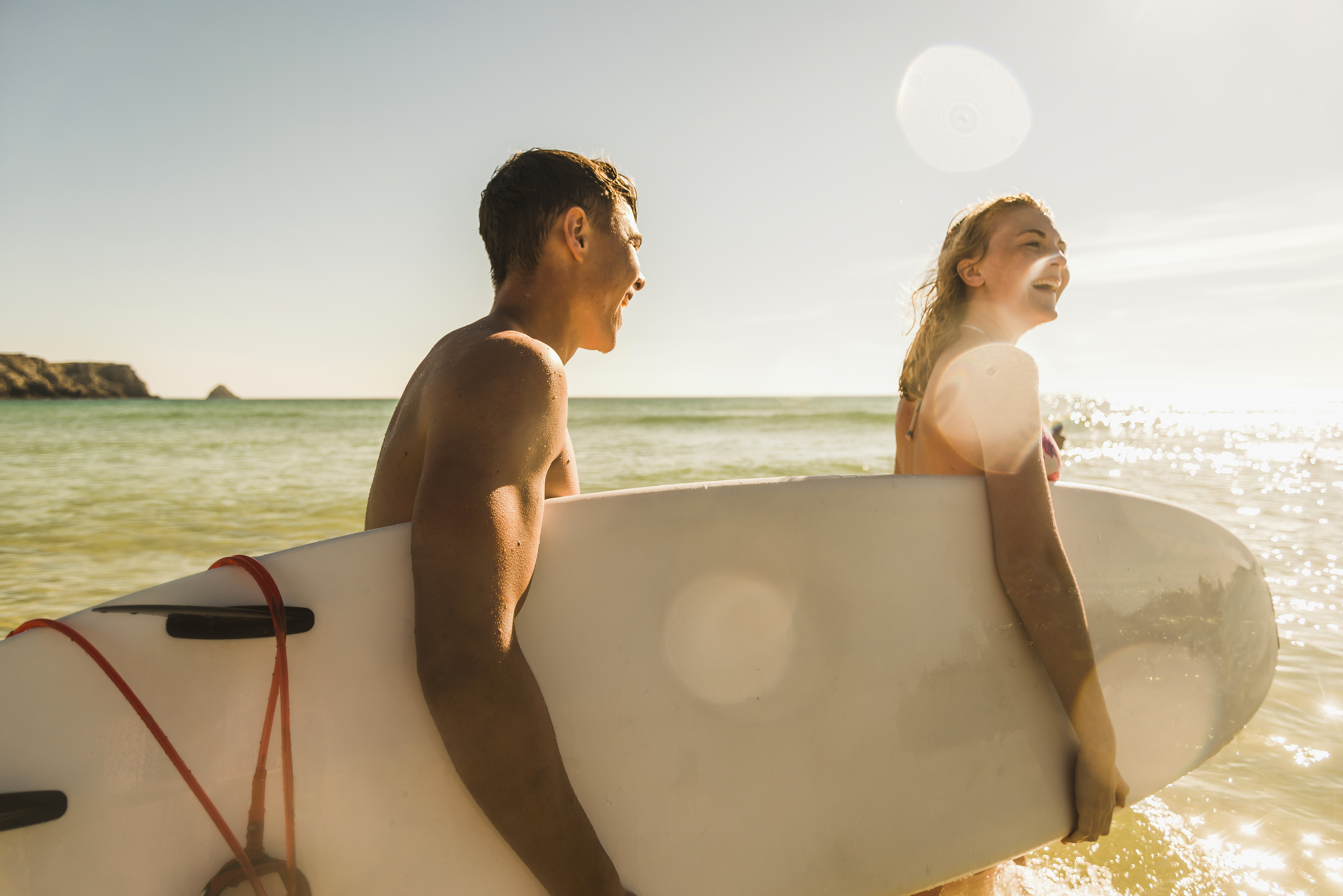 Teenage couple carrying surfboard at the sea